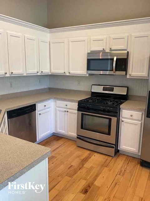 A kitchen with white cabinets and a stove top oven.