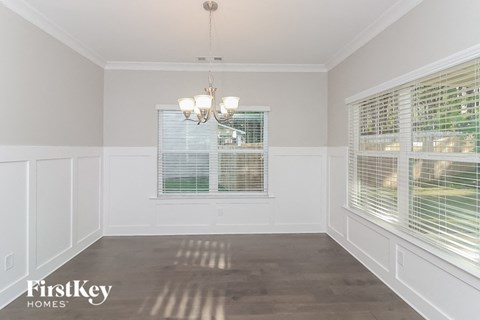 a dining room with two windows and a chandelier