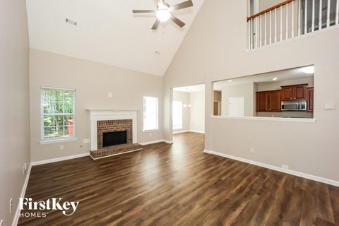 an empty living room with a fireplace and a ceiling fan