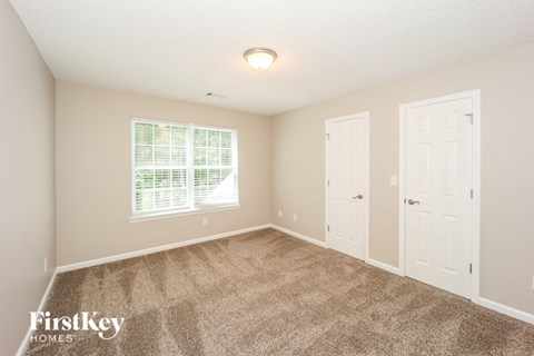 a bedroom with carpet and two doors and a window