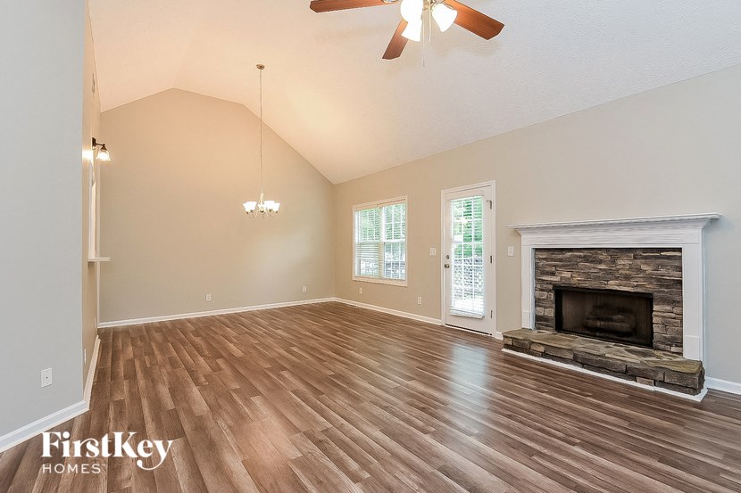 an empty living room with a fireplace and wooden floors