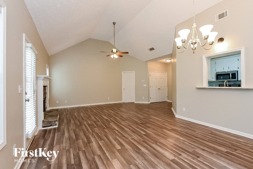 a spacious living room with hardwood floors and a ceiling fan