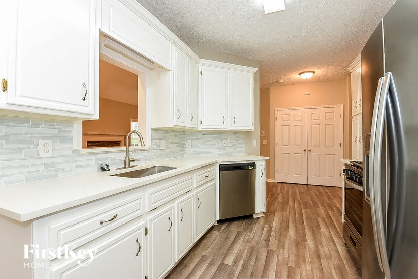 a kitchen with white cabinets and a sink and a refrigerator