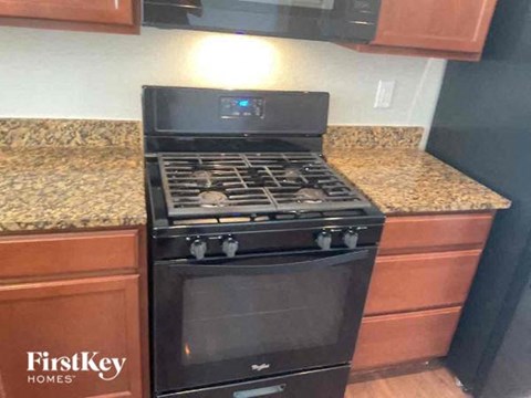 A black stove top oven with four burners and a glass door is in a kitchen.
