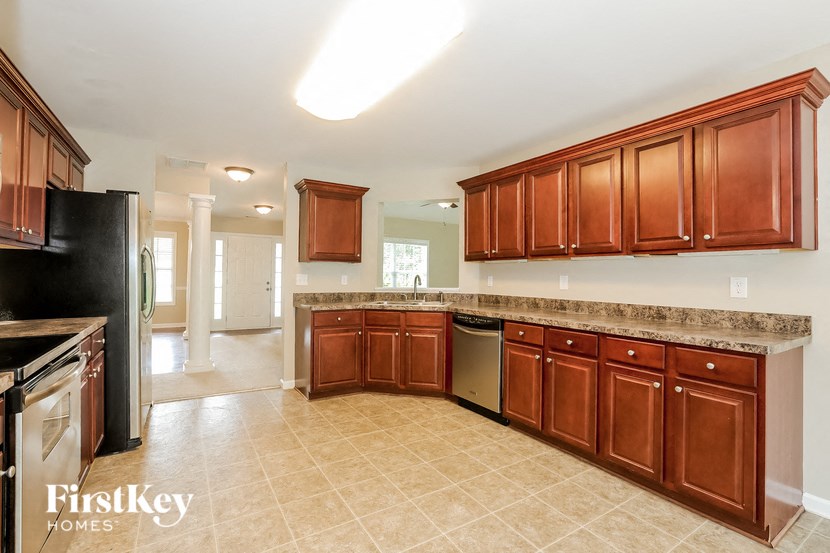A kitchen with brown cabinets and a black refrigerator.
