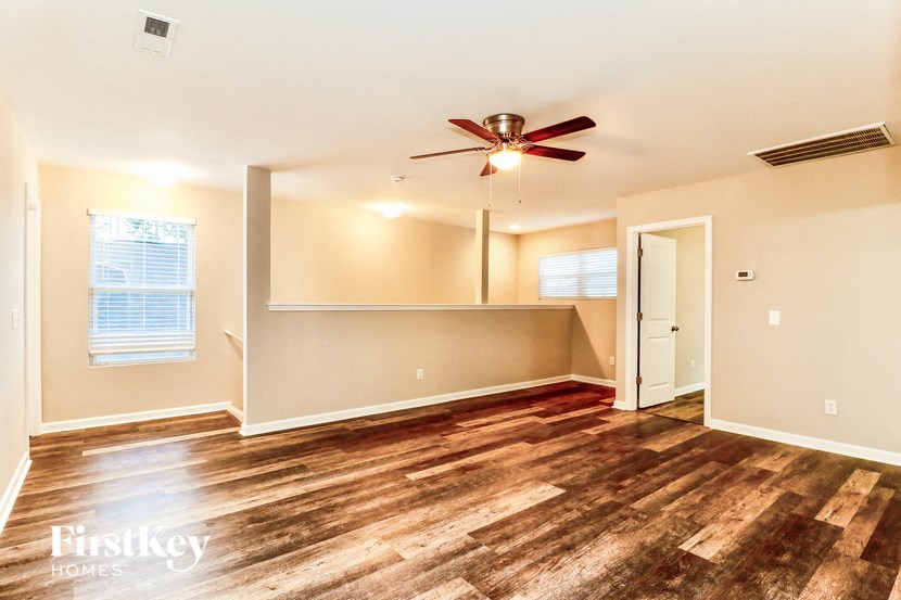 a living room with wood floors and a ceiling fan