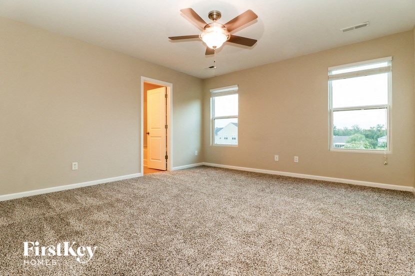 the master bedroom has a ceiling fan and a carpeted floor