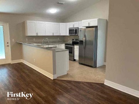 A kitchen with wooden floors and a stainless steel refrigerator.