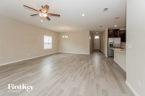 A spacious room with a ceiling fan and lighting fixture.