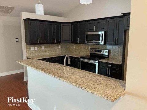 A kitchen with granite countertops and black cabinets.