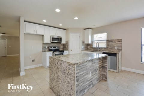 A kitchen with a granite counter top and a stone backsplash.