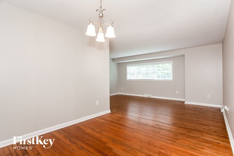 an empty living room with wood flooring and a window