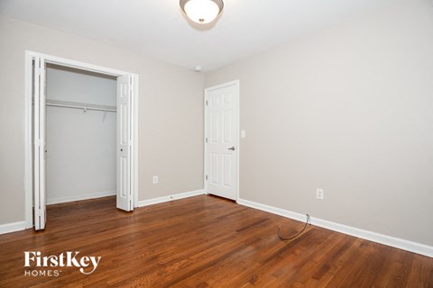 a bedroom with wood flooring and a closet