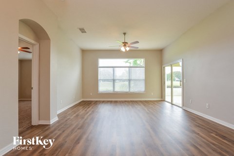 A spacious room with wooden floors and a ceiling fan.