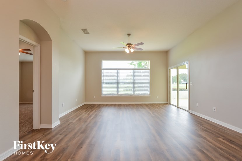 A spacious room with wooden floors and a ceiling fan.