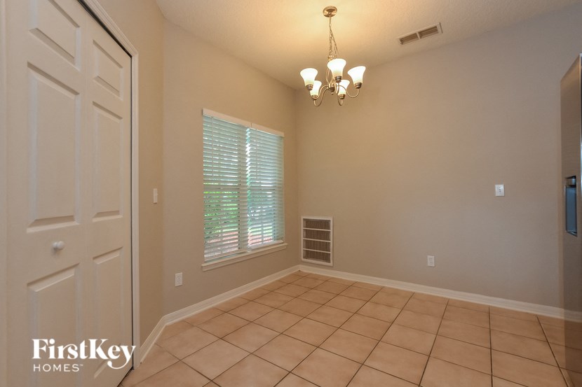 A room with a chandelier, a door, and a window with blinds.