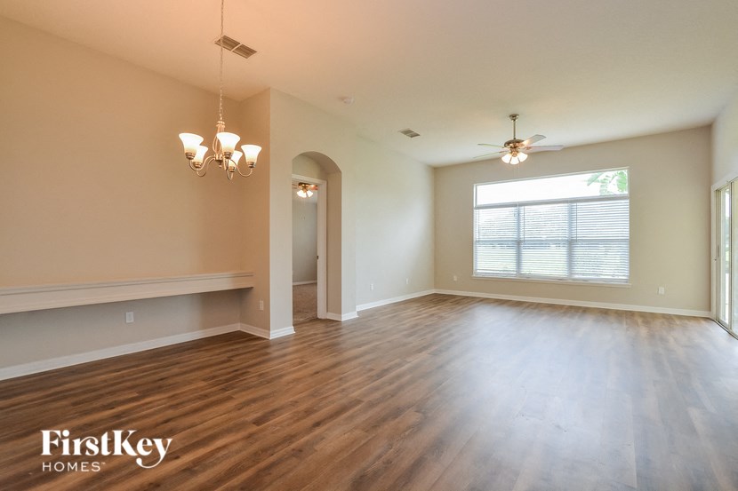 A spacious room with wooden floors and a ceiling fan.