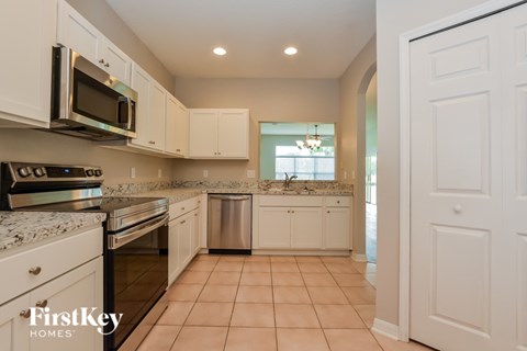 A kitchen with white cabinets and appliances.