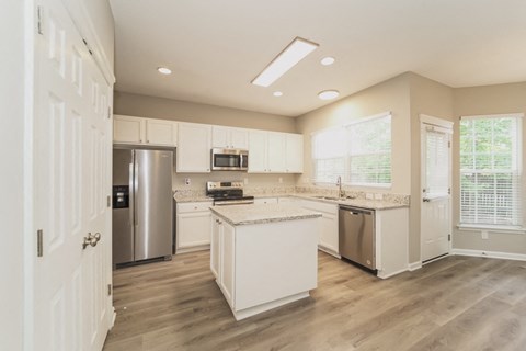 A kitchen with white cabinets and a wooden floor.