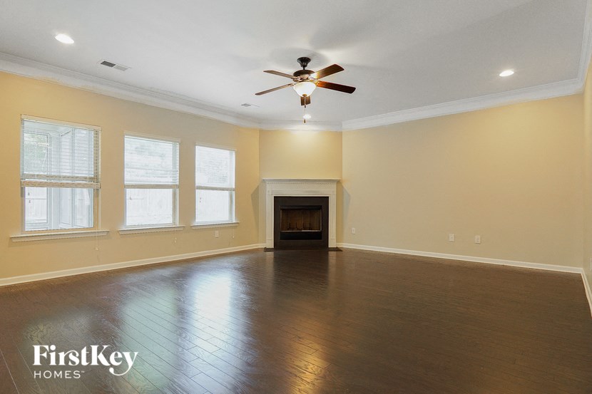 a empty living room with a ceiling fan and a fireplace