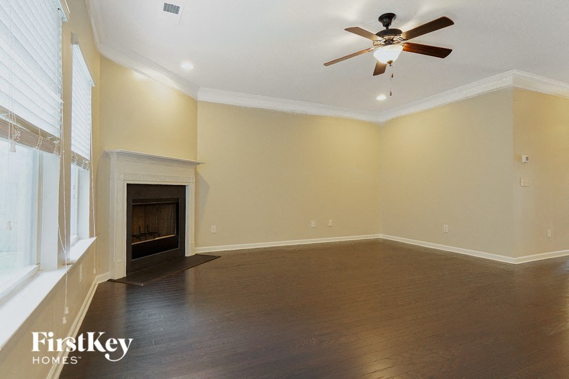 a empty living room with a ceiling fan and a fireplace