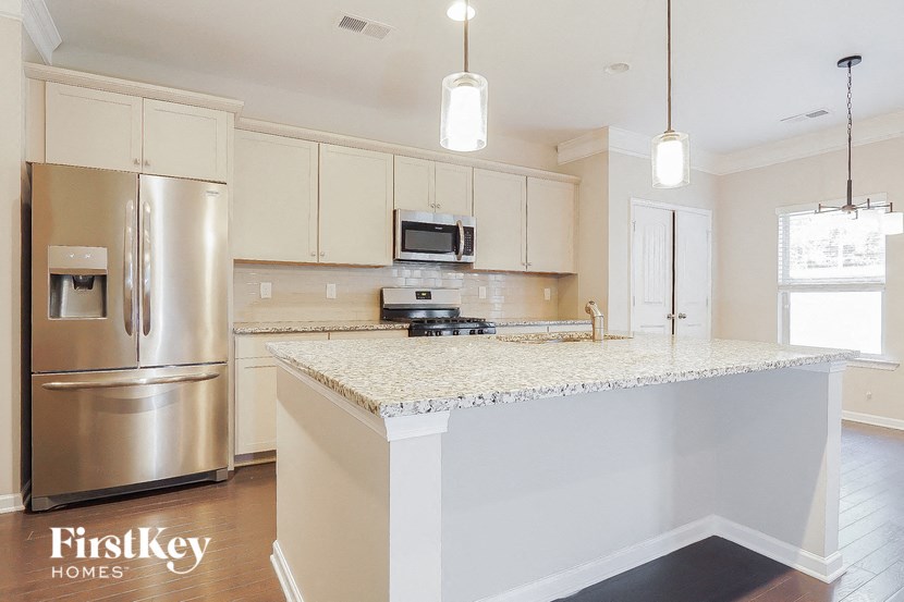 a white kitchen with stainless steel appliances and a marble counter top