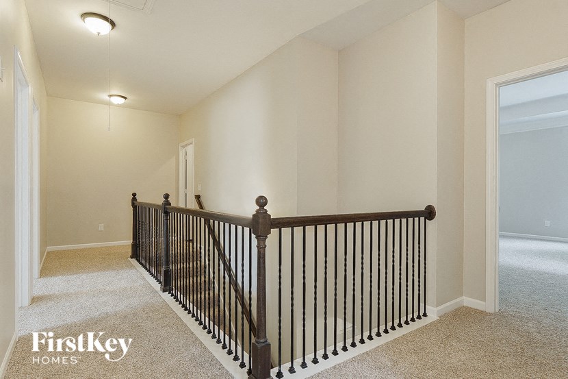 the landing of the loft has a wrought iron railing and carpeted flooring