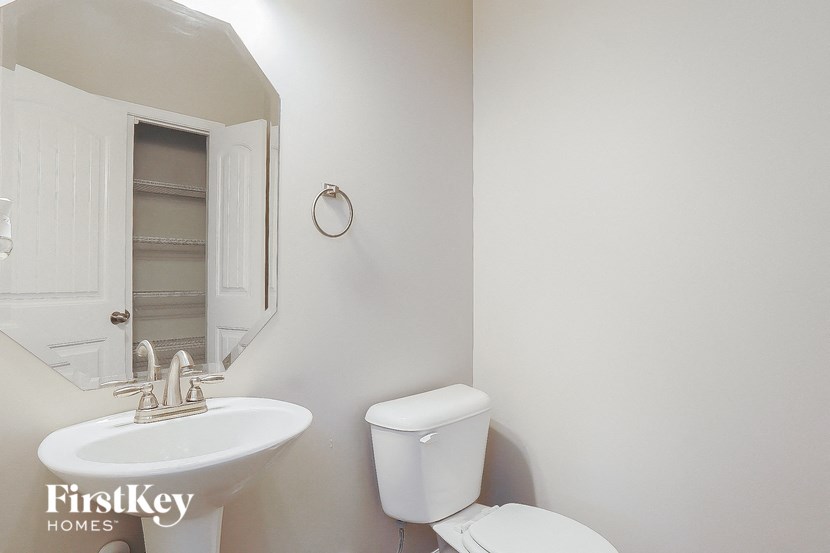 a white bathroom with a sink toilet and a mirror