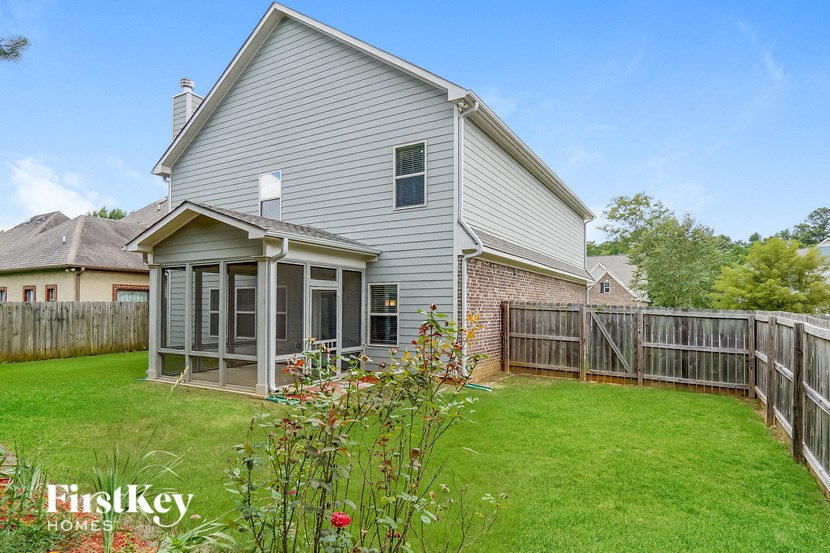 a backyard with a house and a fence and a green lawn
