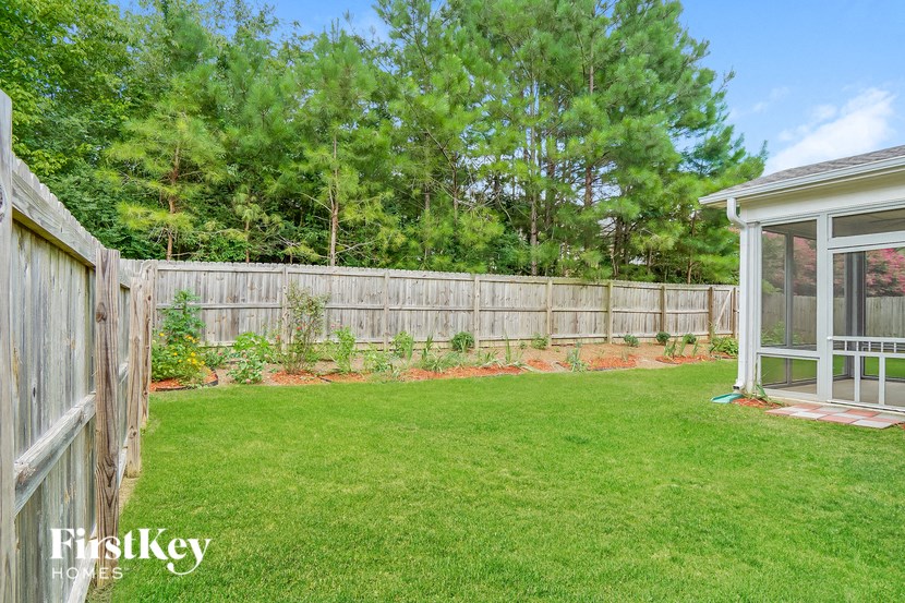 a backyard with a wooden fence and a lawn and a greenhouse