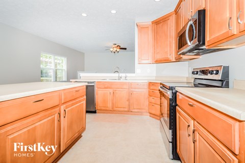 A kitchen with orange cabinets and a stove top oven.