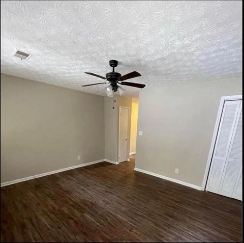 an empty living room with a ceiling fan and wood floors
