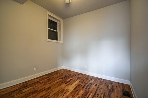 an empty room with wooden floors and a window