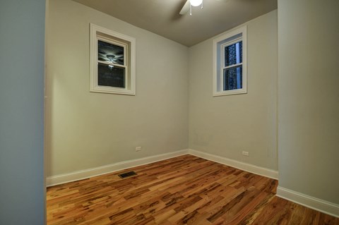 a empty room with wooden floors and two windows
