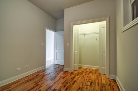 an empty bedroom with wood floors and a closet