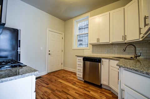 an empty kitchen with white cabinets and a stainless steel dishwasher