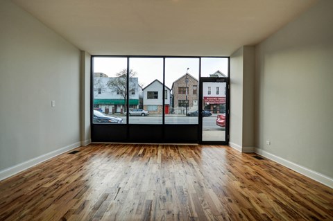 an empty living room with wood floors and large windows