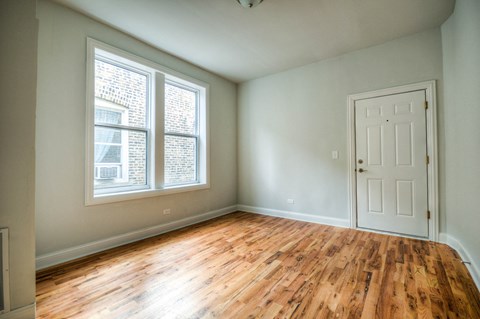an empty living room with wood floors and a white door