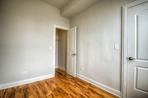 an empty bedroom with wood floors and white walls