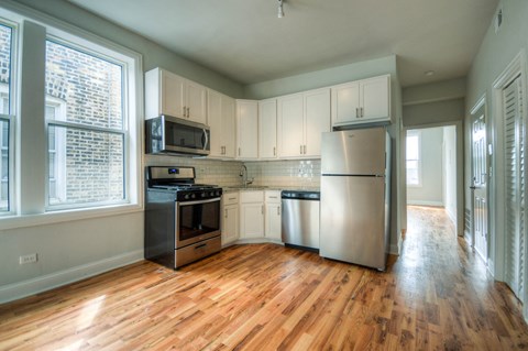 an empty kitchen with stainless steel appliances and white cabinets