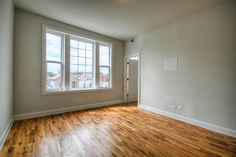 an empty living room with wood floors and a large window