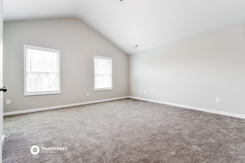 the upstairs bedroom with carpet and two windows
