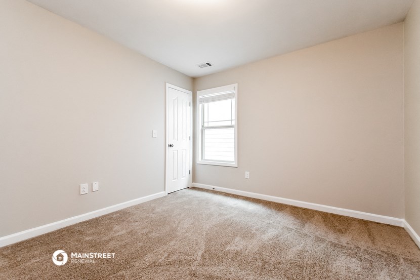 the spacious living room with carpeting and a door to the bedroom