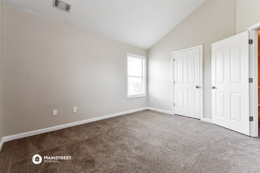 a bedroom with carpet and two doors and a window