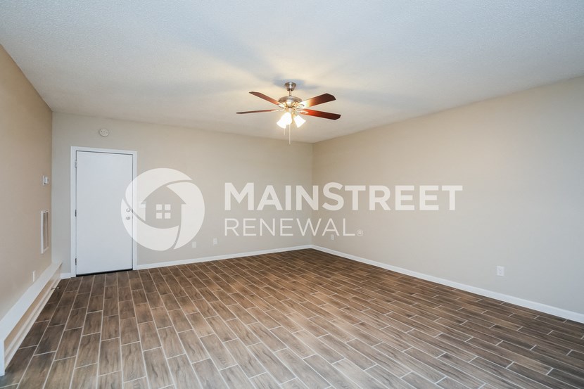 an empty living room with a ceiling fan and a door