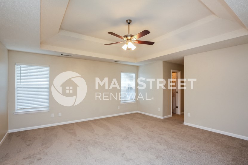 a living room with carpet and a ceiling fan