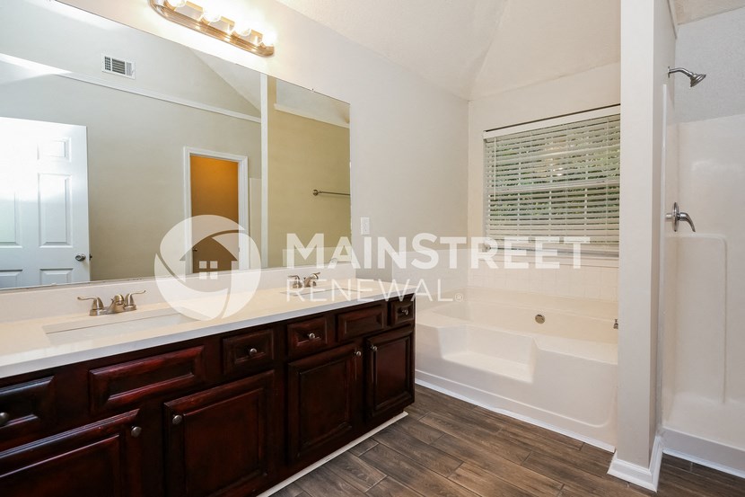 a bathroom with a shower and a sink and a large mirror