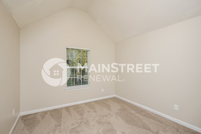 a bedroom with beige carpet and a window