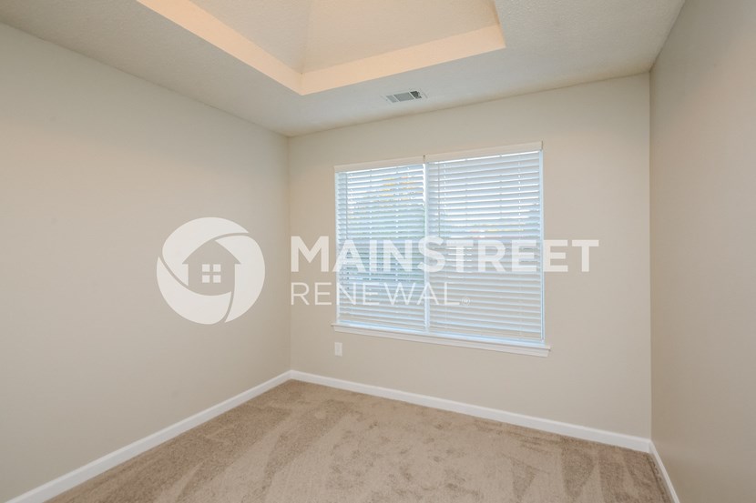 a bedroom with a large window and a carpeted floor