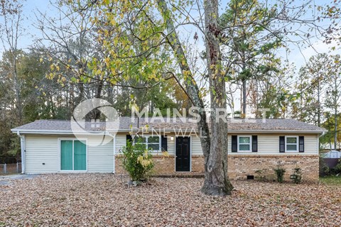 a small brick house with a large tree in the front